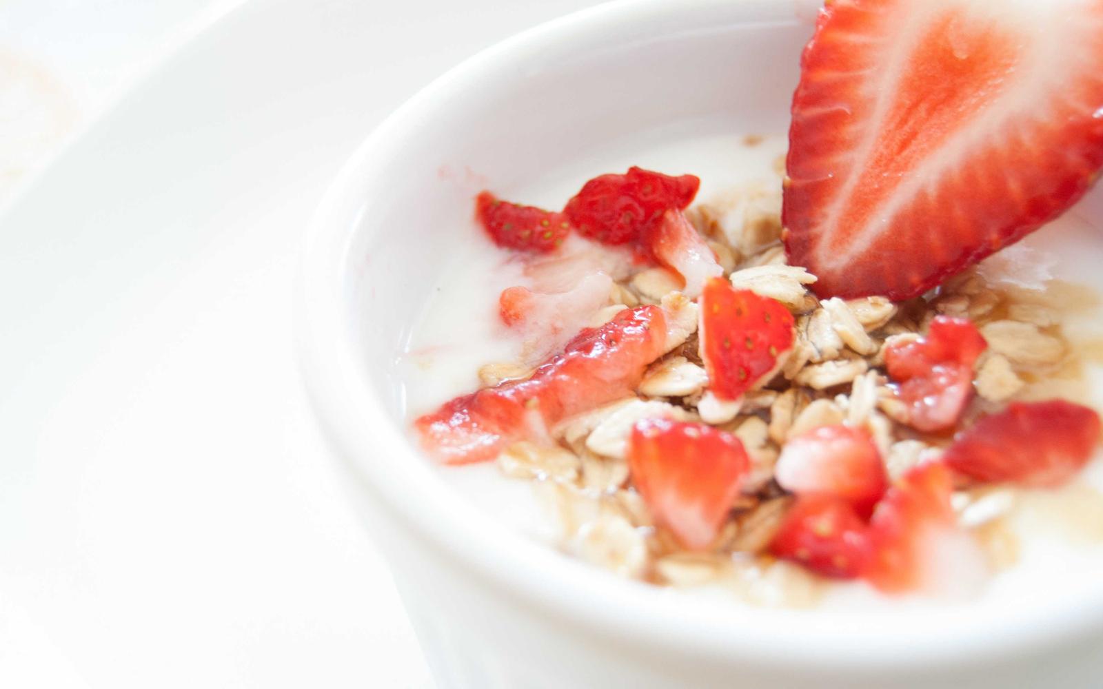 Strawberries and oats over yogurt in a white bowl